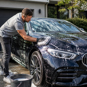 Mann wäscht sein Auto per Hand mit Autoshampoo